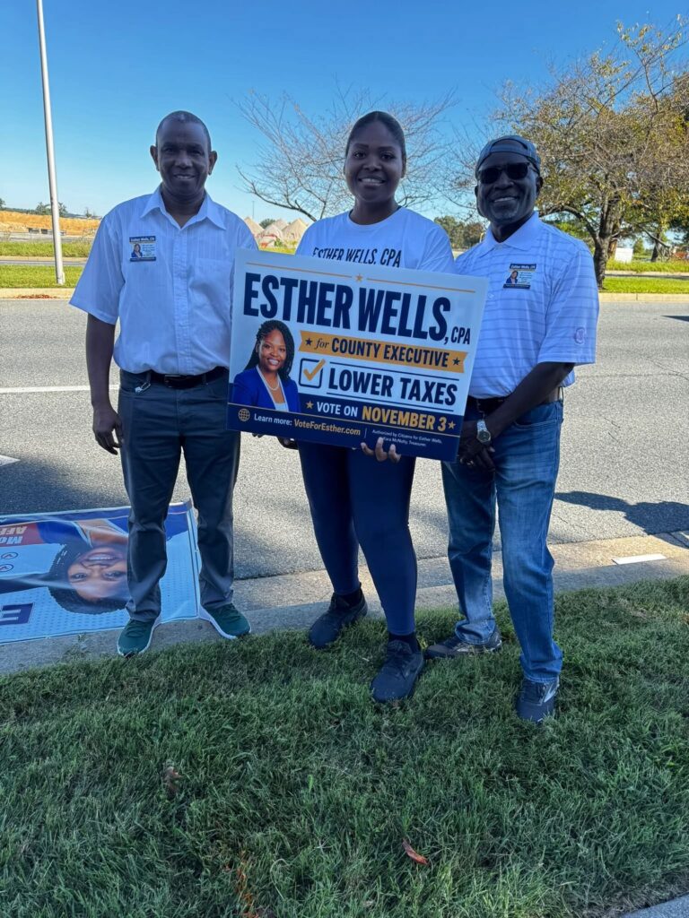 Two volunteers with an Esther Wells campaign sign